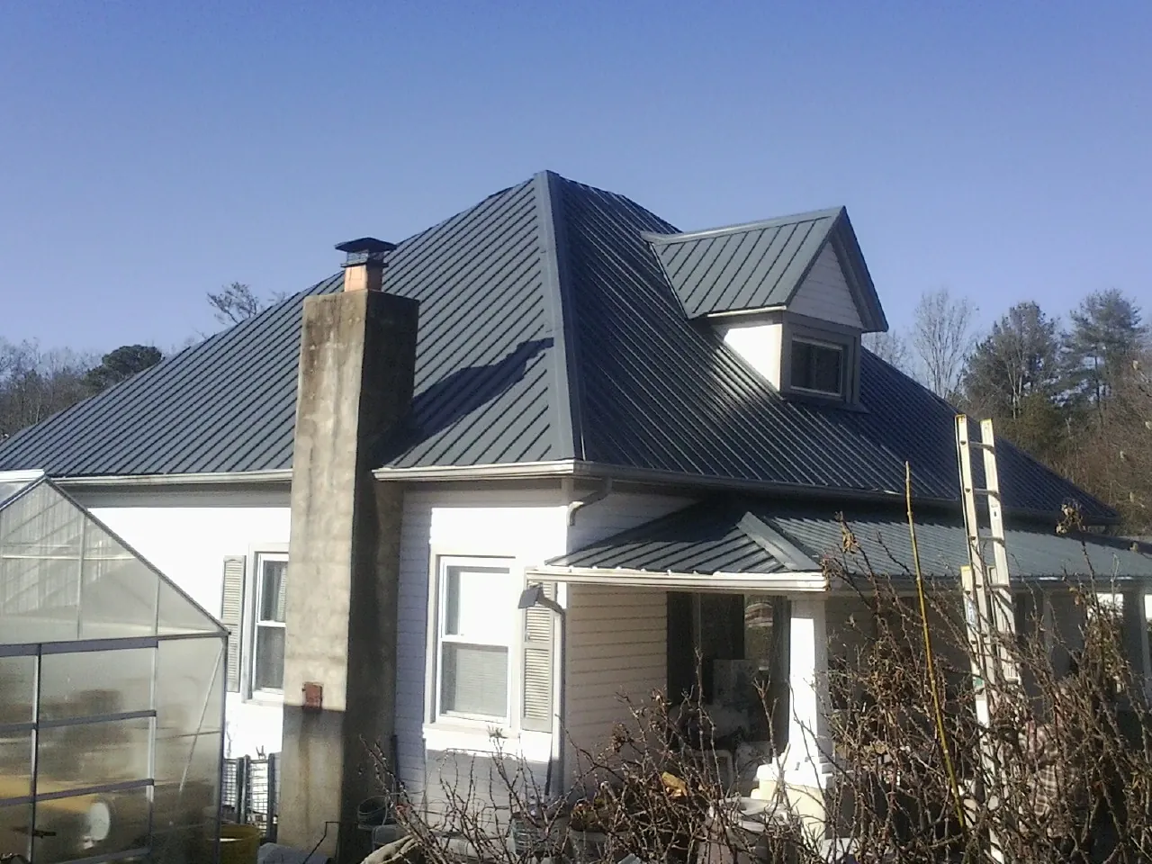 Dark blue standing seam metal roof on a white farmhouse with dormer — Slate & Tile Roof Repair by Roofing Brothers in The Dalles