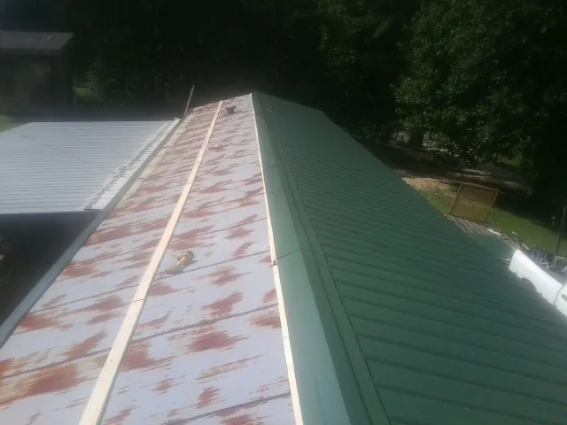 Old rusted panels beside newly installed green metal roofing — Wind Damage Roof Repair by Roofing Brothers in The Dalles
