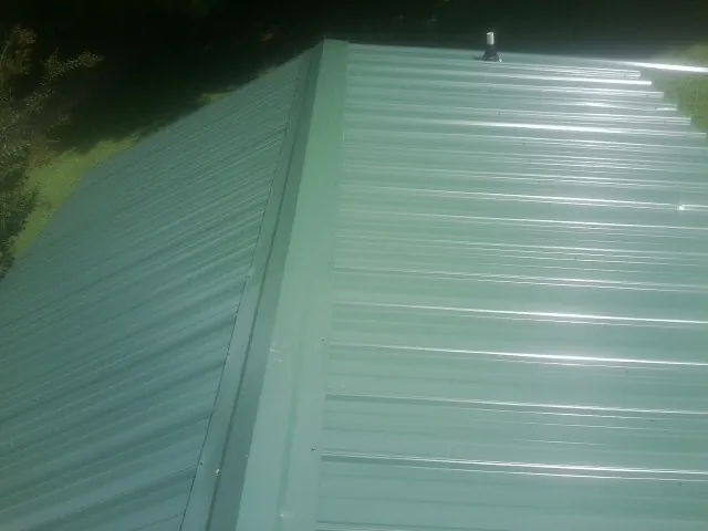 New green metal panels meeting at the ridge of a roof — Flat Roof Repair work by our crew in The Dalles