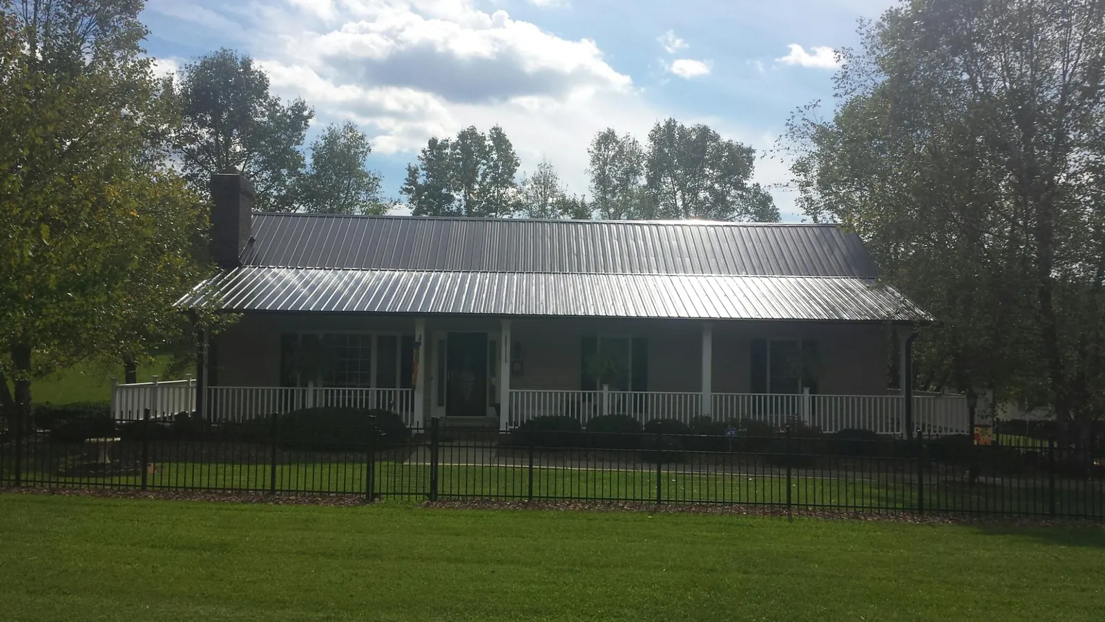 Gray metal roof on a brick ranch with a full width front porch — Gutter Guard Installation work by our crew in The Dalles