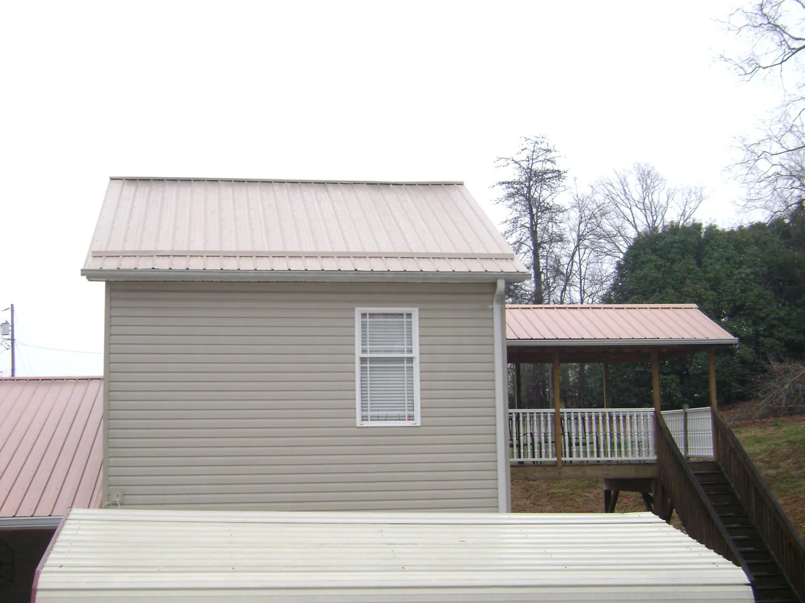 Tan metal roofs on a two story addition and attached porch, from a Roof Replacement job in The Dalles