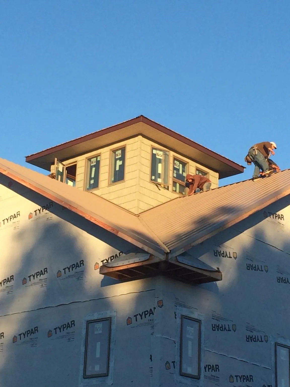 Roofers working around a rooftop cupola on a new metal roof at sunset — Roof Waterproofing in The Dalles by Roofing Brothers